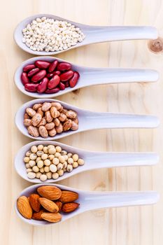 Assortment of beans and lentils in spoon on wooden background. almond, soybean, red kidney bean ,red bean and brown pinto beans .