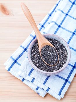 Nutritious chia seeds in ceramic bowl for diet food ingredients setup on wooden background.
