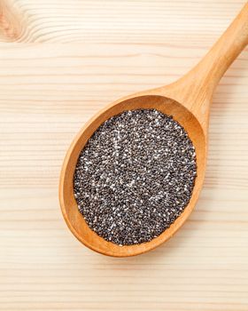 Nutritious chia seeds in wooden spoon for diet food ingredients setup on wooden background.