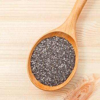 Nutritious chia seeds in wooden spoon for diet food ingredients setup on wooden background.