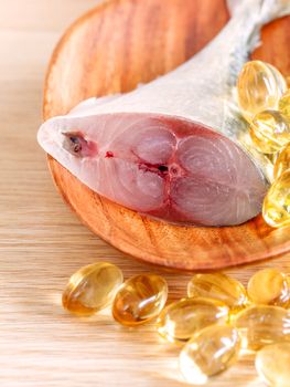 Close up fresh cutting Mackerel in wooden spoon with fish oils capsules . The supplement high vitamin E, omega 3, DHA and EPA. selective focus shallow depth of field .