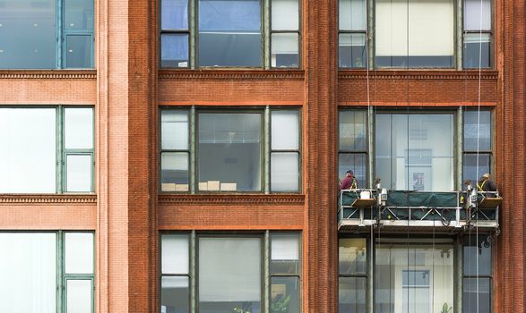 Workers of steeplejack washing windows of the modern building.