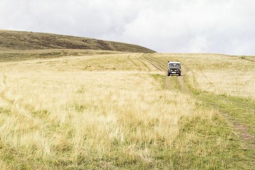 Wide panoramic scenic view at high meadow, mountain valley dry yellow grass, autumn, emptiness,  car in the distance