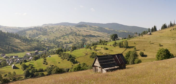 Small settlement in the mountains. Houses outbuildings and fields. Rural nature Mountain river road fence