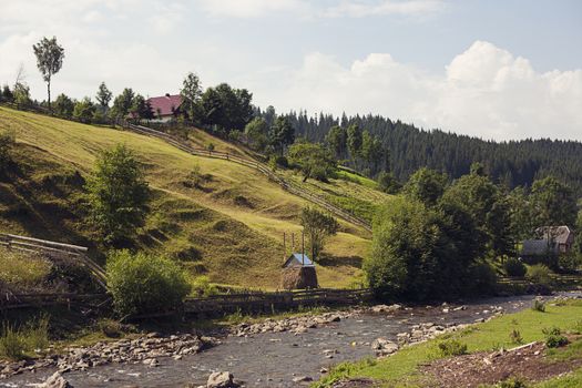 Small settlement in the mountains. Houses outbuildings and fields. Rural nature Mountain river road fence