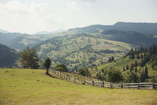 Small settlement in the mountains. Houses outbuildings and fields. Rural nature Mountain river road fence