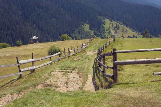 Small settlement in the mountains. Houses outbuildings and fields. Rural nature Mountain river road fence