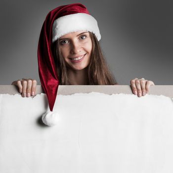 Happy smiling woman in Santa's hat with white blank banner with copy space