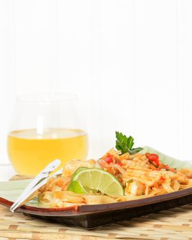 Plate of delicious chicken pad thai garnished with lime.