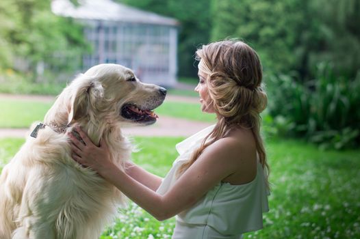 beautiful girl in white dress with a white dog in the garden