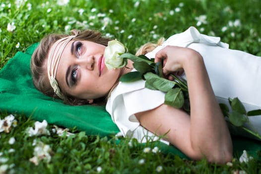 beautiful girl with a white rose in the Park on the grass