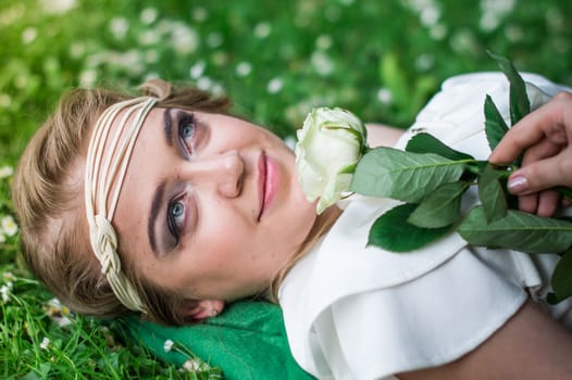 beautiful girl with a white rose in the Park on the grass