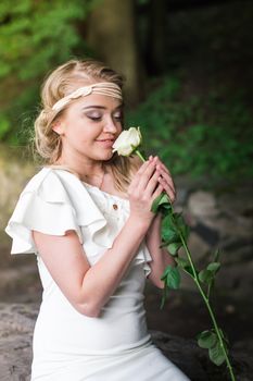 beautiful girl sniffing white rose in the Park