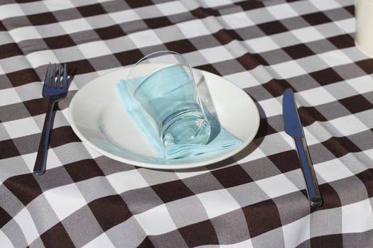 Checked table cover, cutlery, plate, glass 