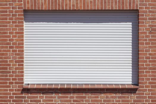 Windows with closed shutters on a red House Wall