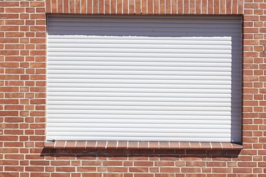 Windows with closed shutters on a red House Wall