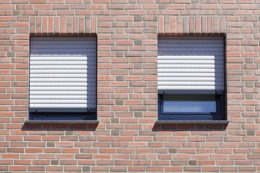 Windows with closed shutters on a red House Wall