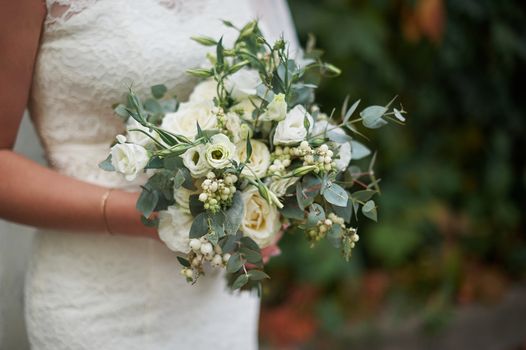 bride holding a beautiful wedding bouquet of white roses.