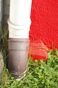  red painted  concrete house wall  with water pipe