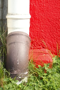  red painted  concrete house wall  with water pipe