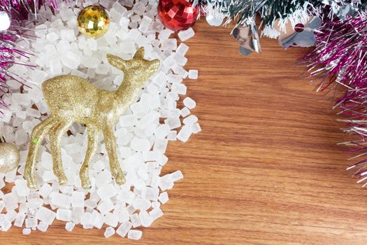 Deer color gold on a pile of white crystalline. Red and yellow Christmas Balls Ornaments on wood,