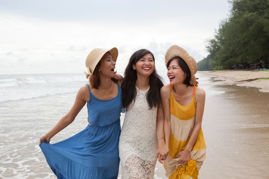 portrait of young asian woman with happiness emotion wearing beautiful dress walking on sea beach and laughing joyful use for people relaxing vacation on destination