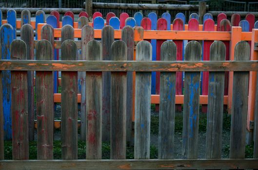 An old colored wooden fence in a playground