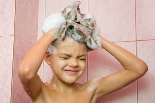 Seven-year girl washing her hair with shampoo