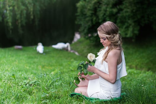 beautiful girl with a white rose in the Park on the grass