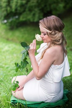 beautiful girl sniffing white rose in the Park