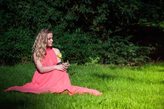 beautiful girl with a white rose in the Park on the grass