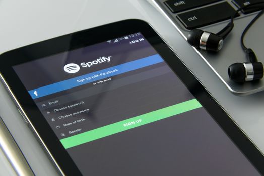 Krynica Poland - November 03, 2016: Spotify app in a mobile phone, close to a laptop. Spotify is one of the most popular music service app on the world.