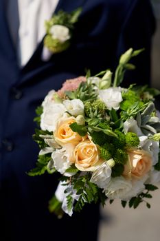 groom holds the beautiful brides wedding bouquet