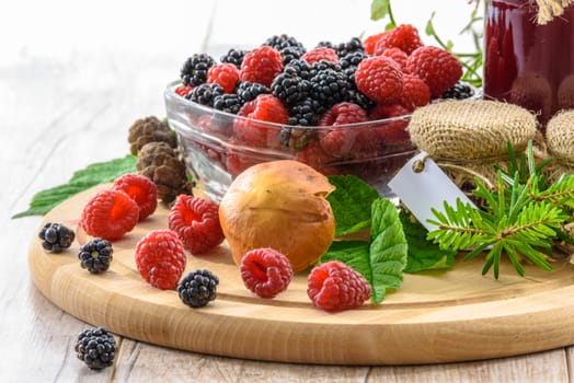 Bowl full of blackberries and raspberries, and preparations homework on a wooden table vintage