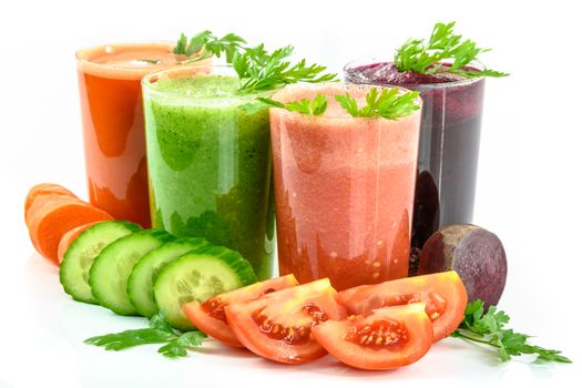 Four vegetable juices in glasses with parsley and vegetables isolated on a white background