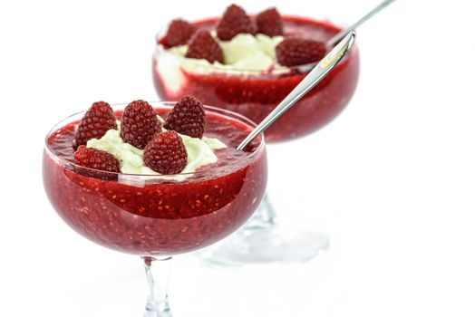 Raspberries and whipped cream in glass cups isolated on white background