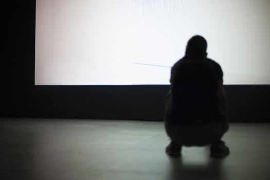 Silhouette of a man sat on a wall background