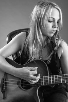 Photo of a beautiful blond female playing an acoustic guitar.