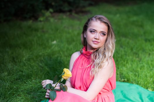 beautiful girl with a white rose in the Park on the grass