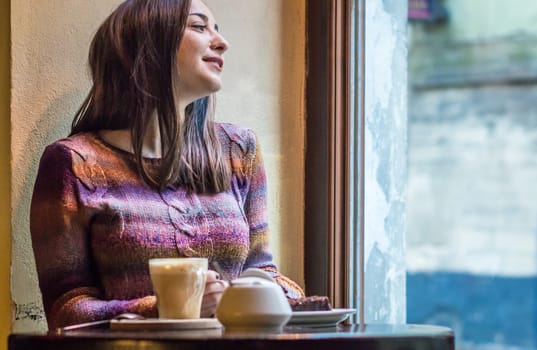 beautiful girl drink coffee and look out the window