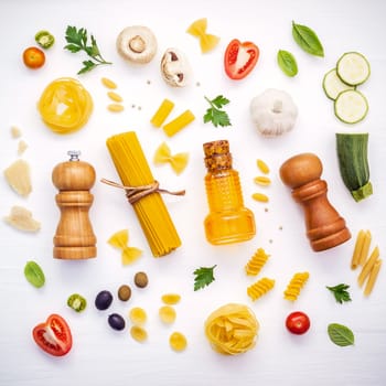 Italian food concept .Various kind of pasta with ingredients sweet basil ,tomato ,garlic ,parsley ,bay leaves ,pepper ,champignon,zucchini and parmesan cheese on white wooden background flat lay.