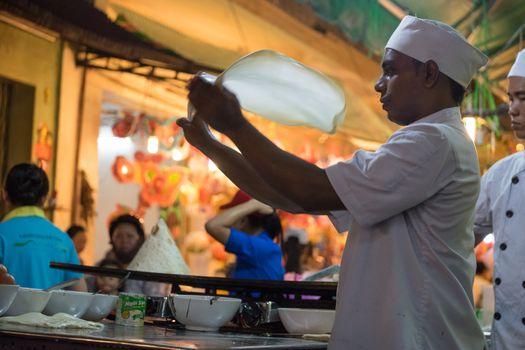 A malaysian chef is baking on street with smile