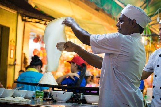 A malaysian chef is baking on street with smile