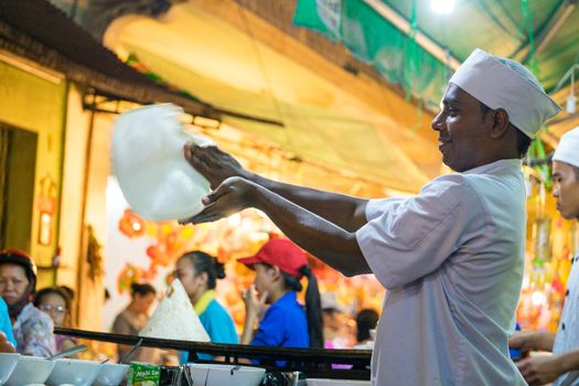 A malaysian chef is baking on street with smile