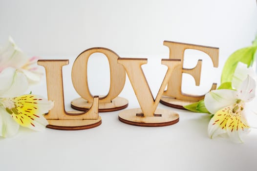 wooden letters Love with flowers on a white background.