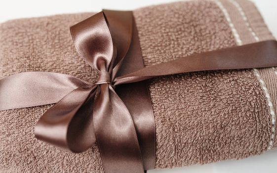 Brown towel tied with a brown bow on white