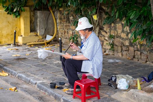 Old man drawing in the street of Hoi An. Hoian is recognized as a World Heritage Site by UNESCO