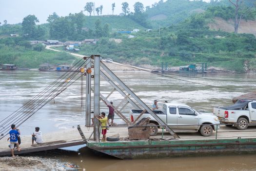 Unidentified ferry is carrying trucks across the Mekong River on June 10,2015 in Houay xai harbor, Bokeo , Laos pdr