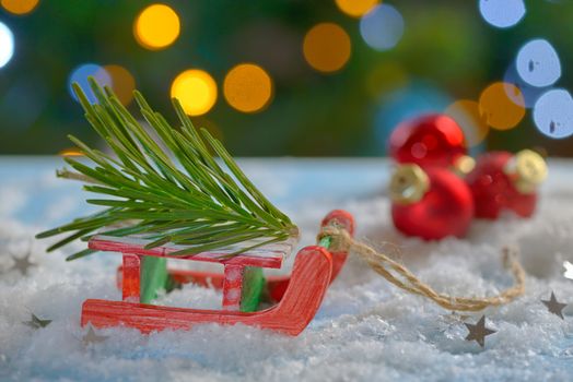 Red sleigh toy and Christmas tree on fake snow