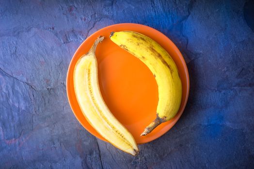 Half a banana lies on a orange plate horizontal